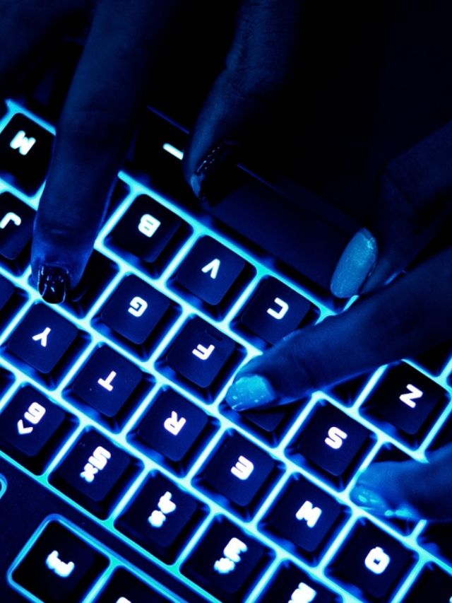 Uma fotografia de mãos femininas utilizando um teclado com led azul.