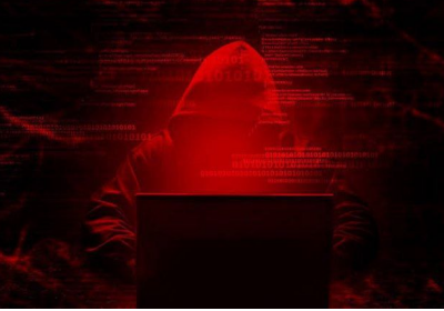 Hacker in red-lit environment using laptop.
