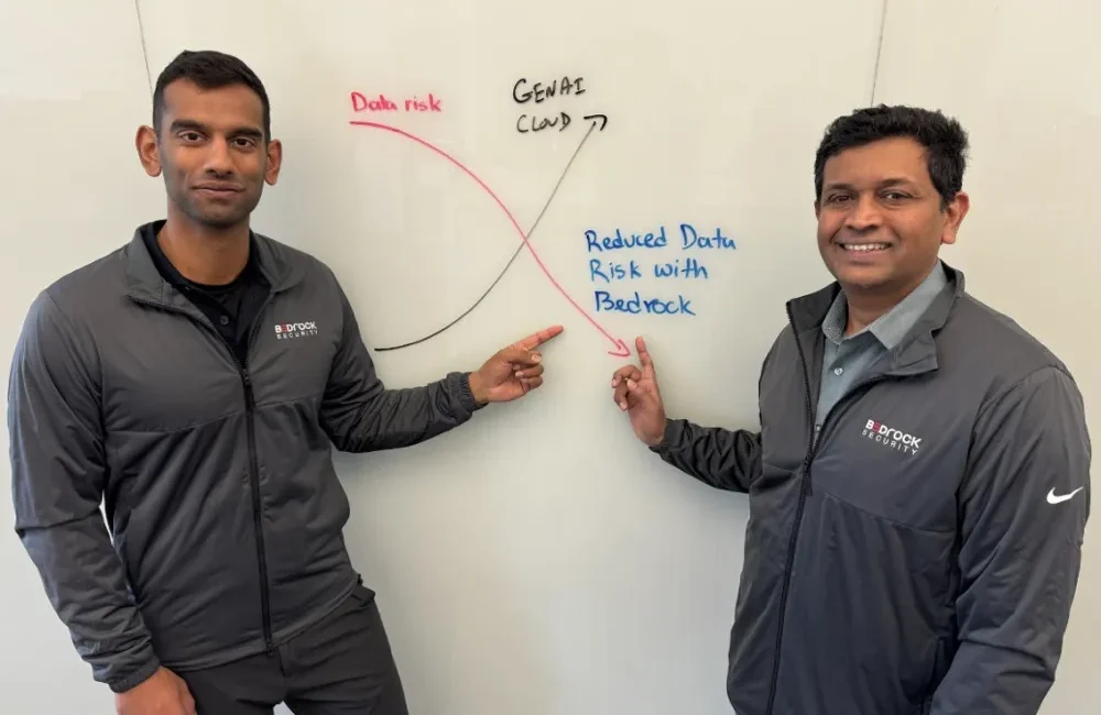 Two men pointing at whiteboard graph.