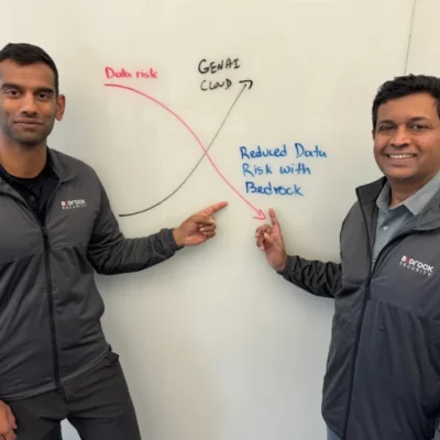 Two men pointing at whiteboard graph.